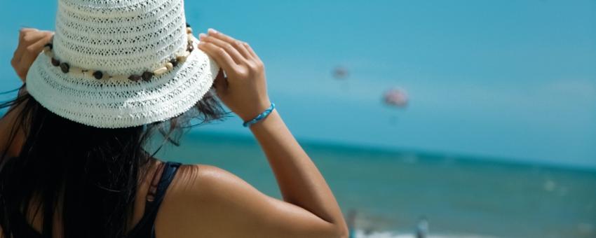 Woman facing away from camera with ocean and beach in the background